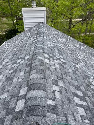 A close up of a roof with a chimney and trees in the background.