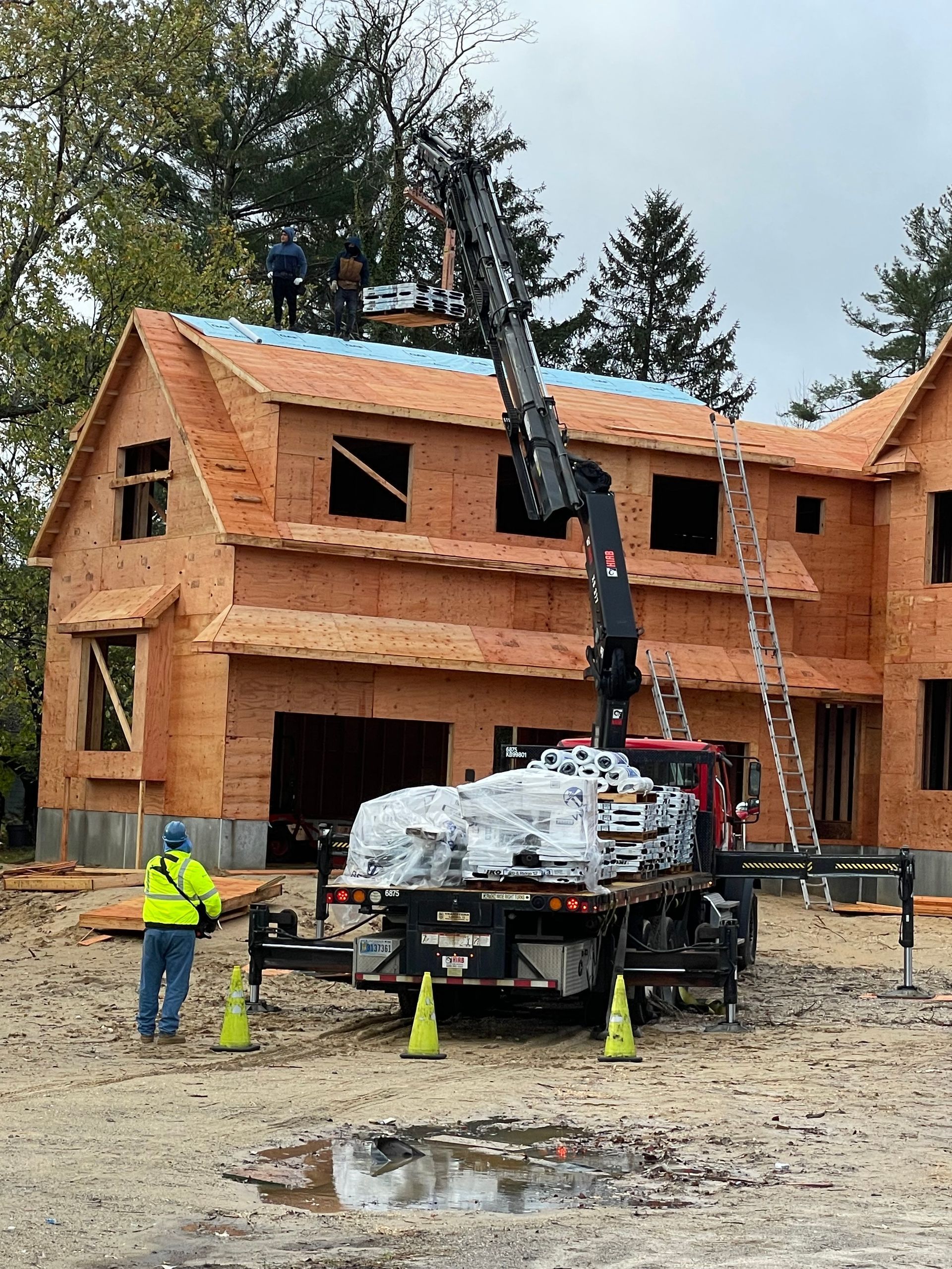 A crane is lifting a roof on a house under construction.