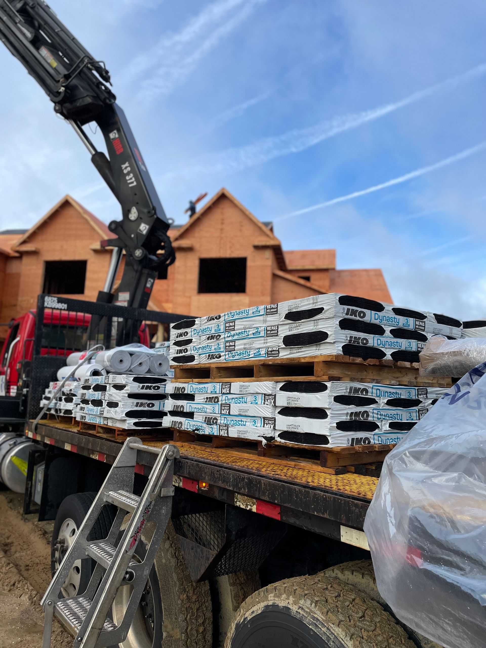 A truck is loaded with pallets of bricks and a crane.