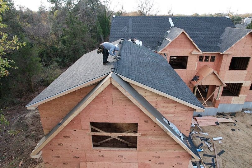 A man is working on the roof of a house under construction.