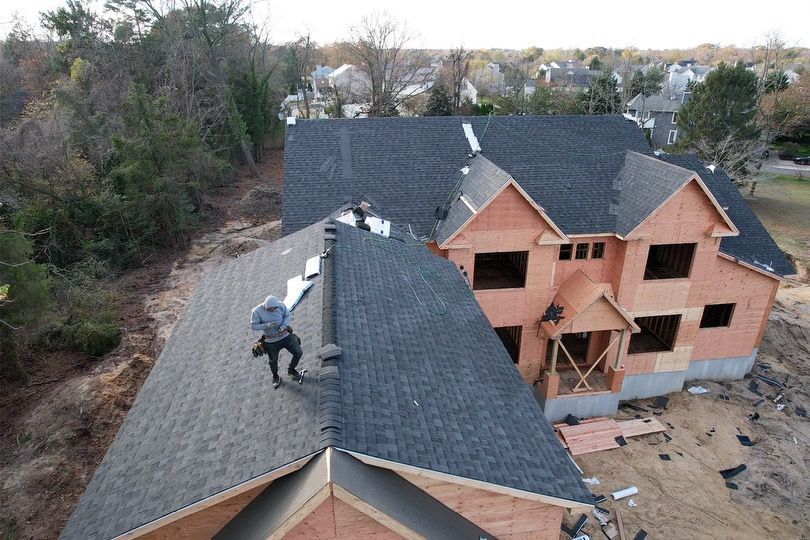 A man is standing on the roof of a house under construction.
