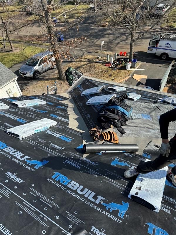 A man is sitting on the roof of a house.