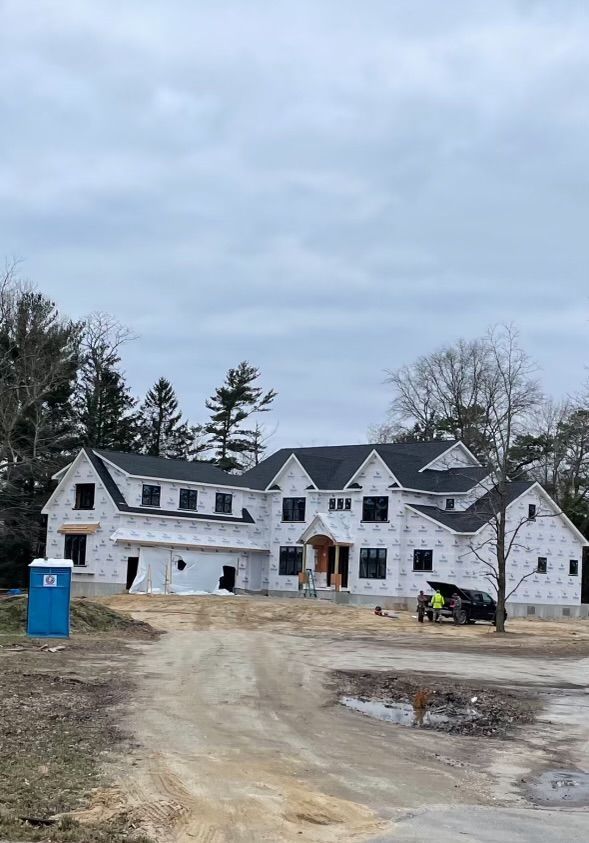 A large white house is being built on a dirt road.