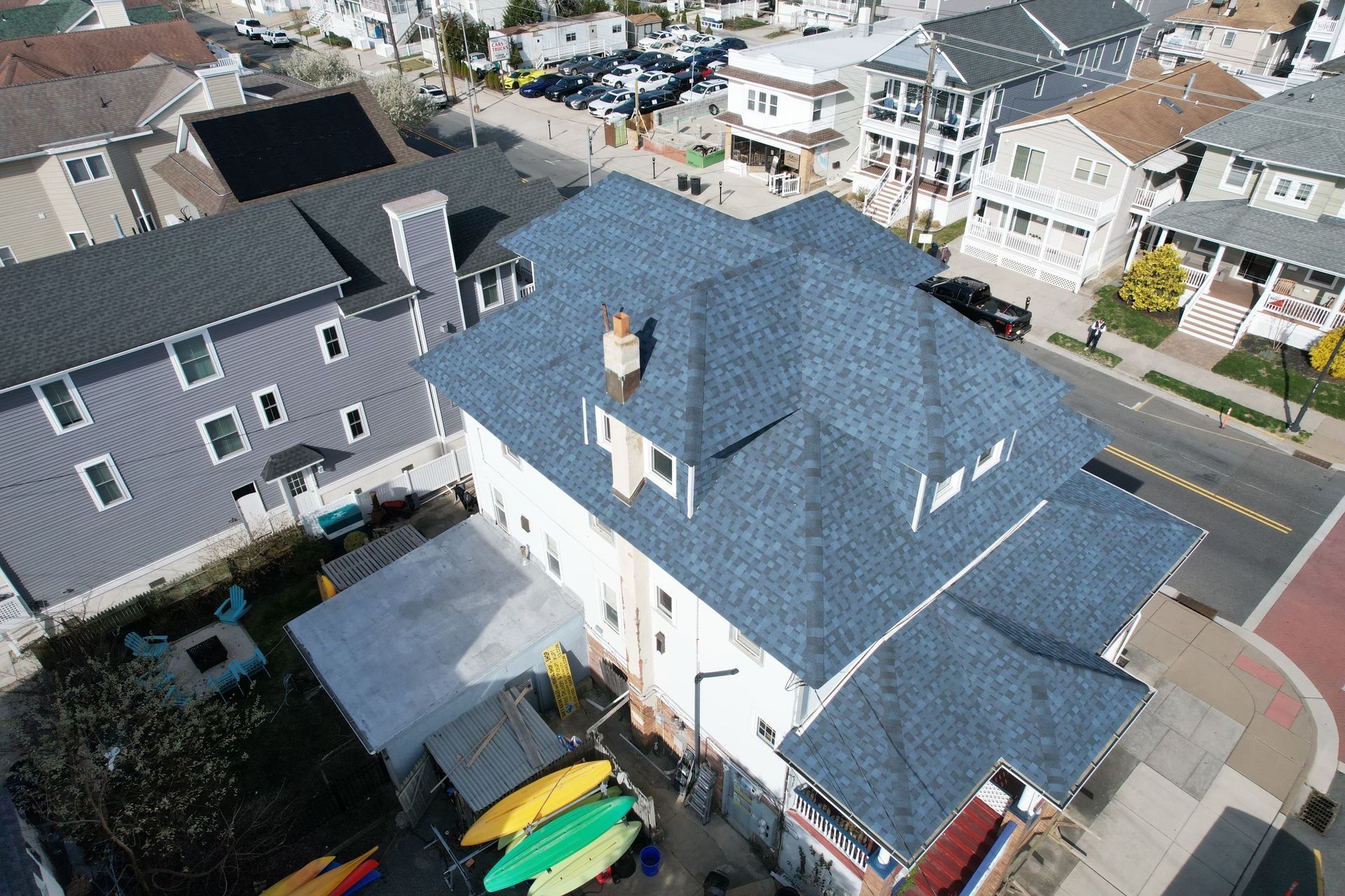 An aerial view of a house with a blue roof in a residential area.
