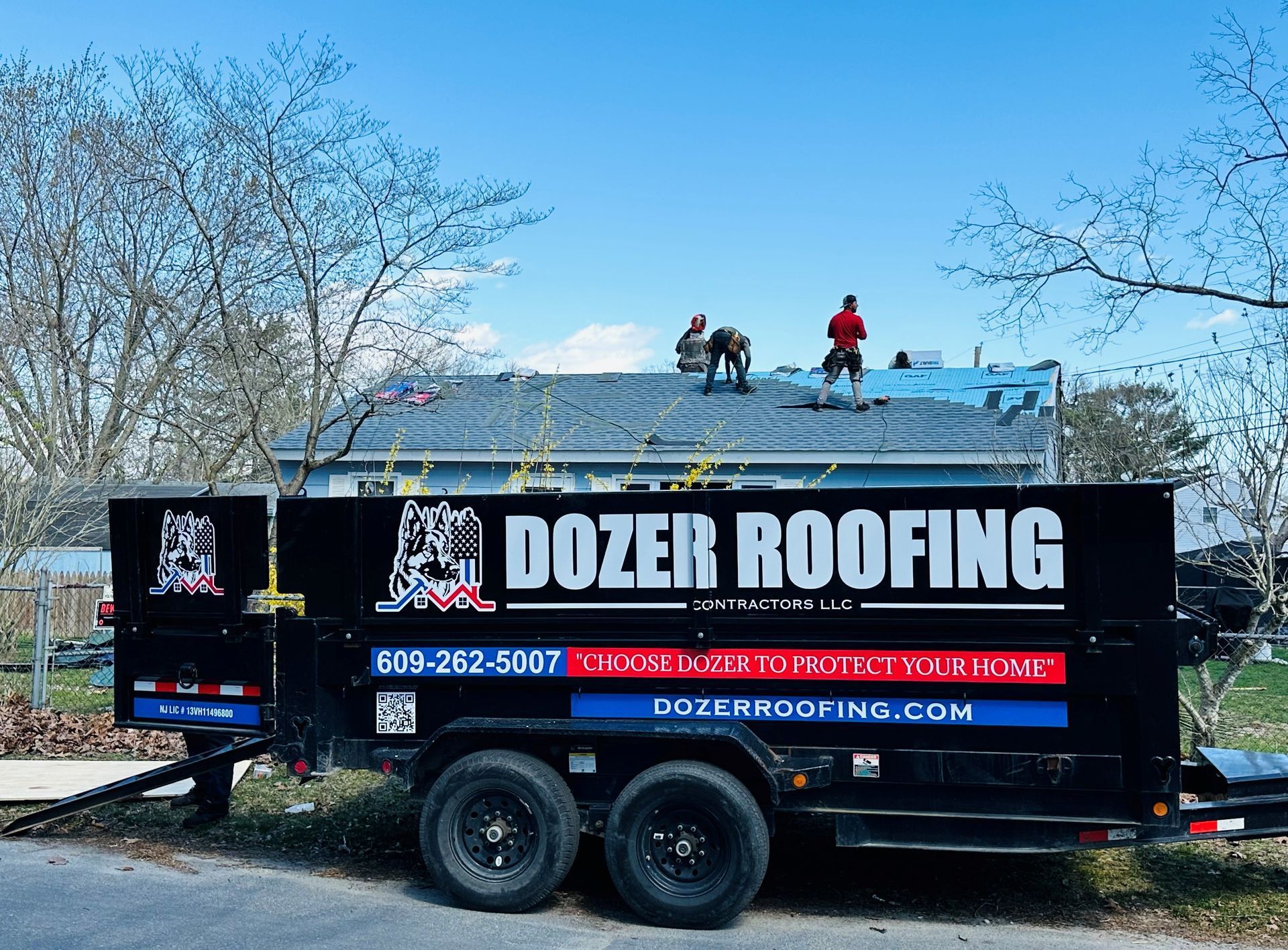 A dozer roofing trailer is parked on the side of the road