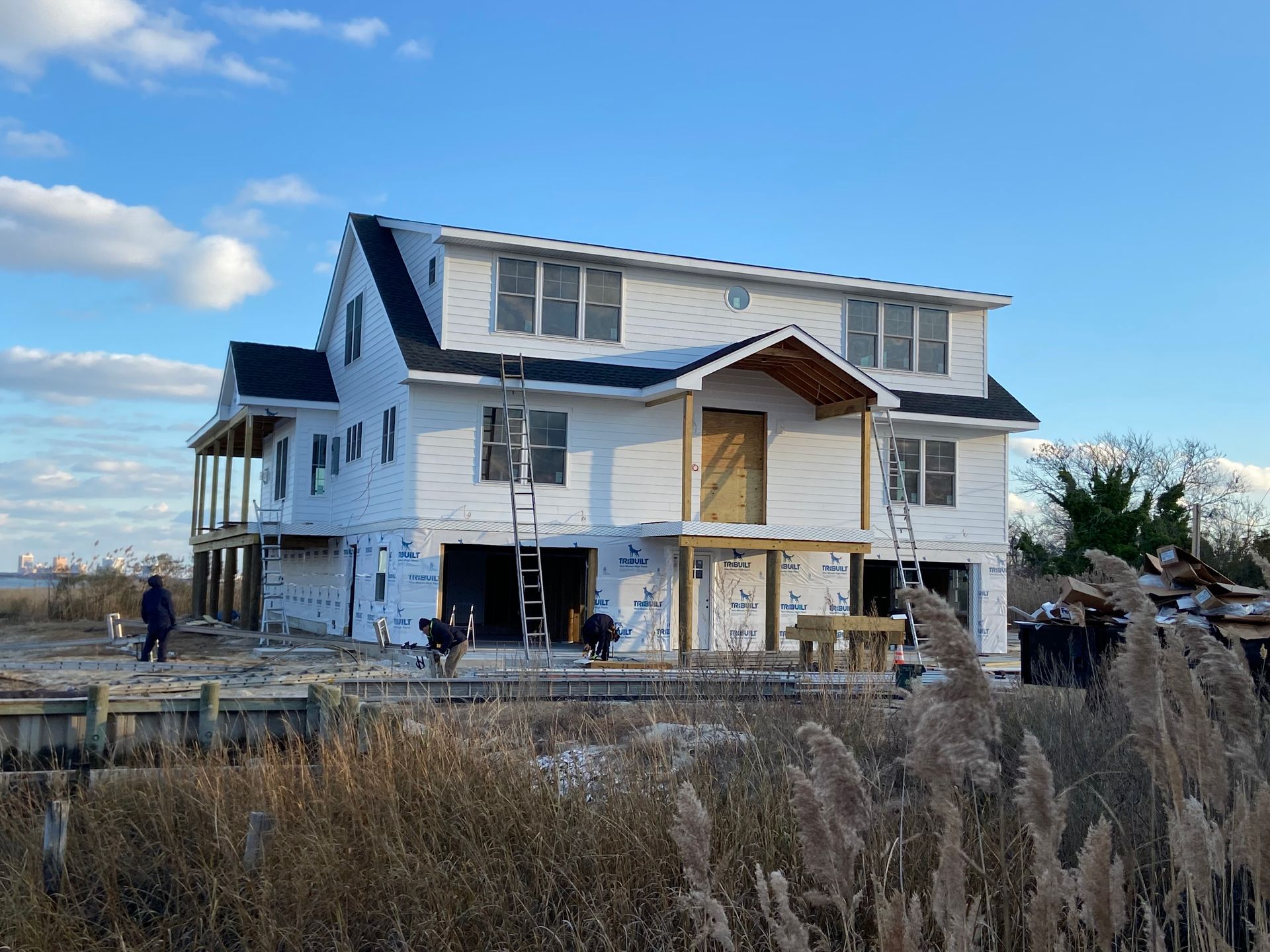 A large white house is being built in the middle of a field.
