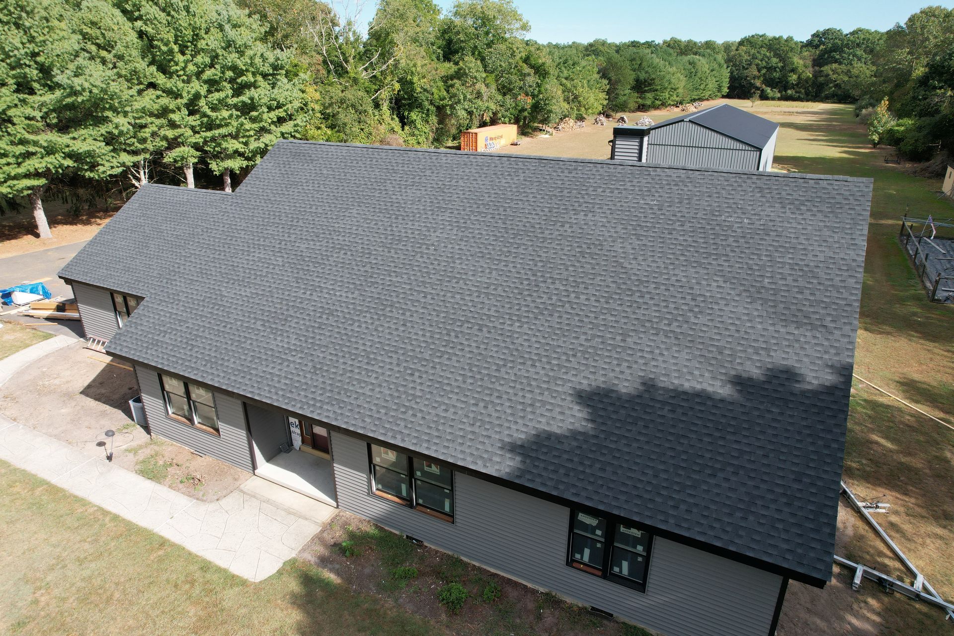 An aerial view of a house with a black roof surrounded by trees.