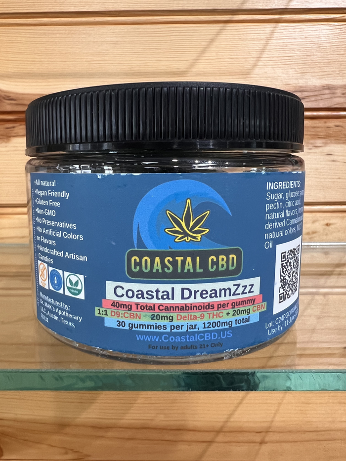 Coastal CBD jar with black lid and blue label, sitting on a wooden shelf.