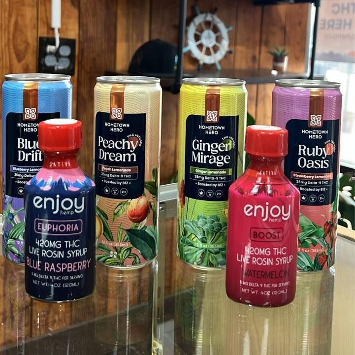 Assorted colorful THC vape bottles and cans displayed on a wooden shelf indoors