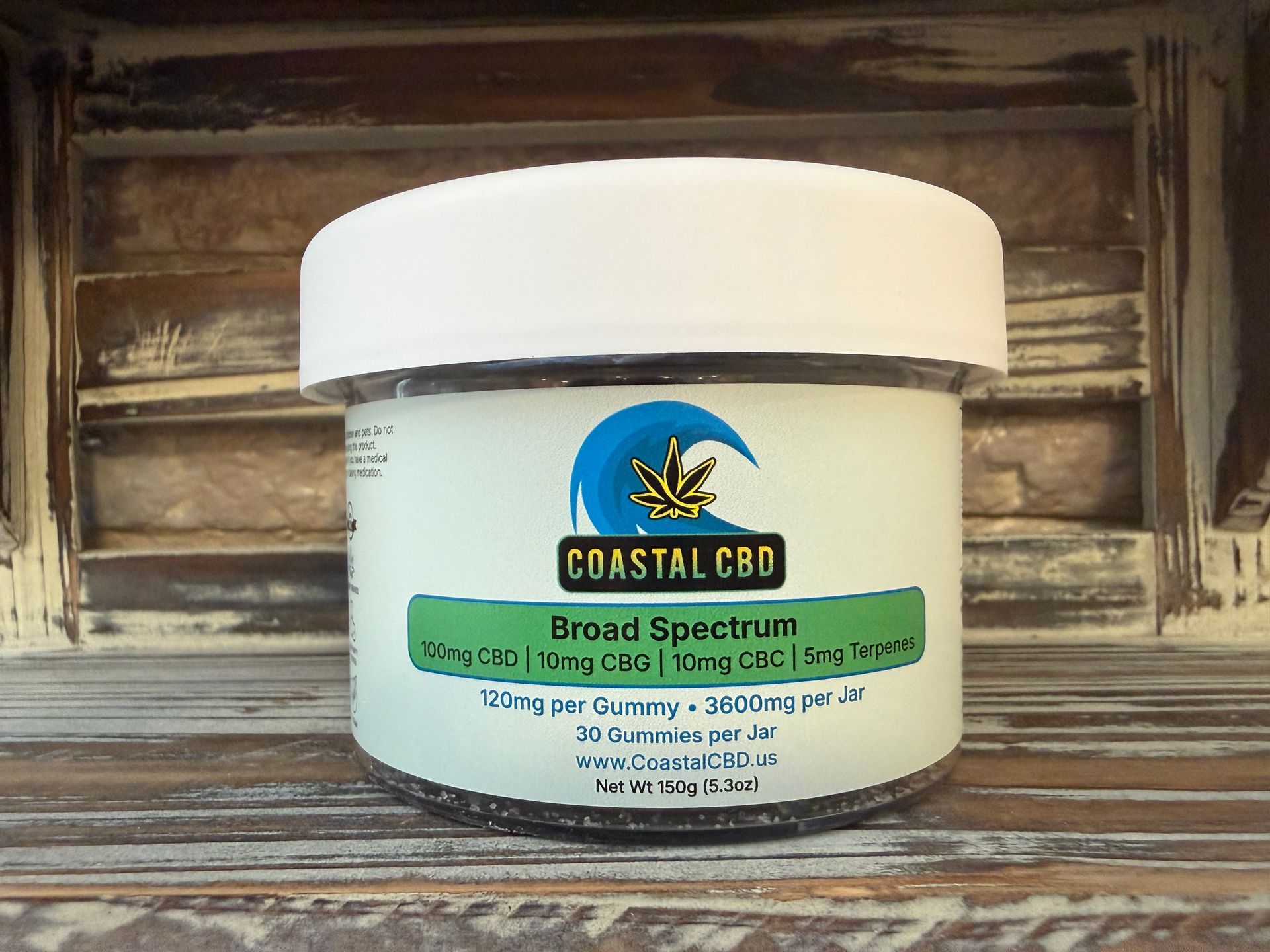 White jar of Coastal CBD broad spectrum cream on a wooden surface