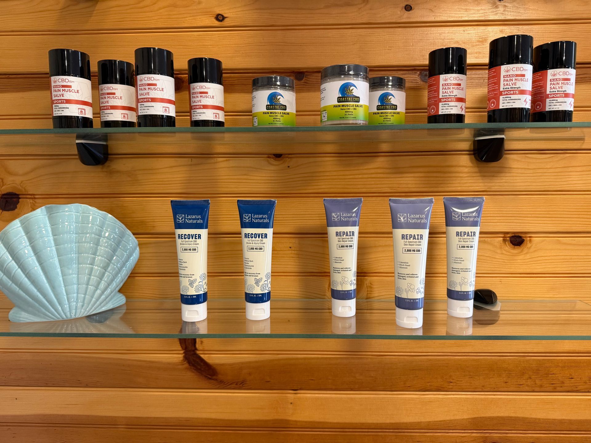 Shelves of products and a seashell decor piece on a wood wall