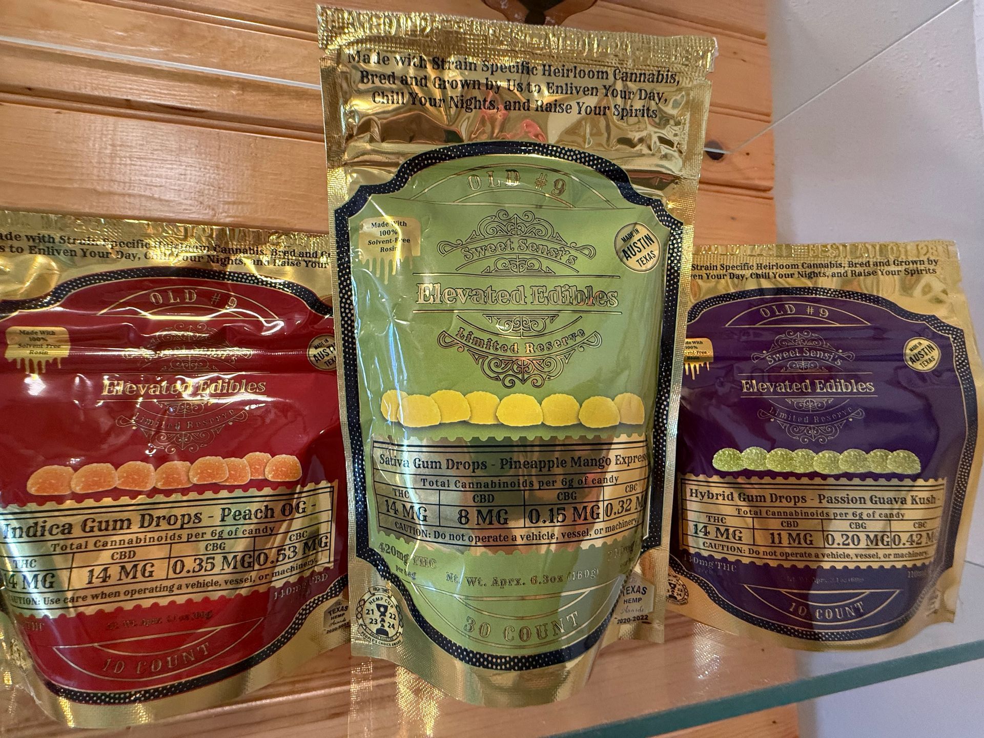 Three colorful standing pouches of packaged on a wooden surface: red, green, and purple.