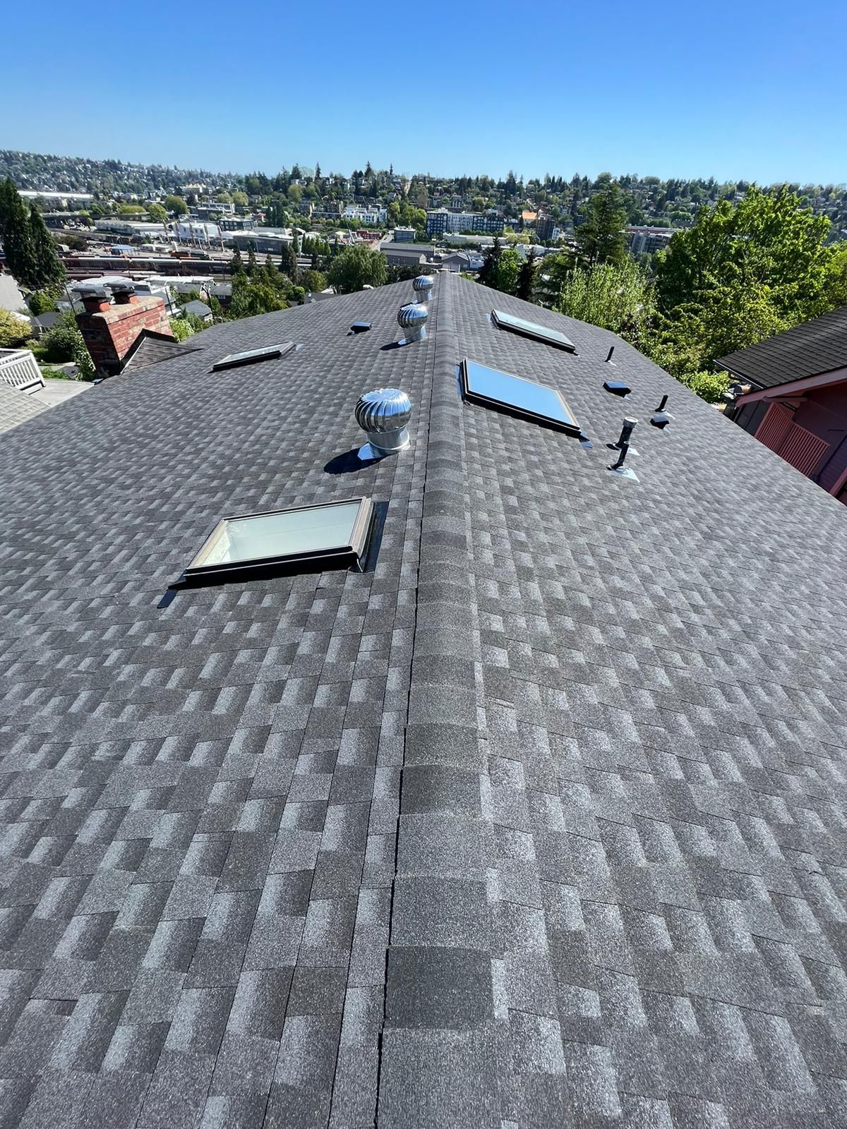 A roof with a lot of skylights on it and a city in the background.