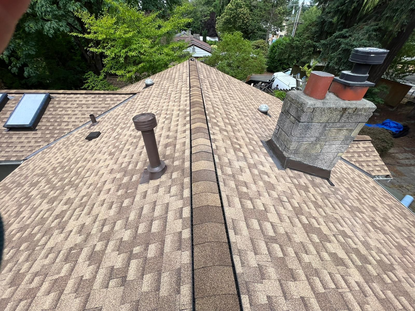 A roof with a chimney and skylights on it.