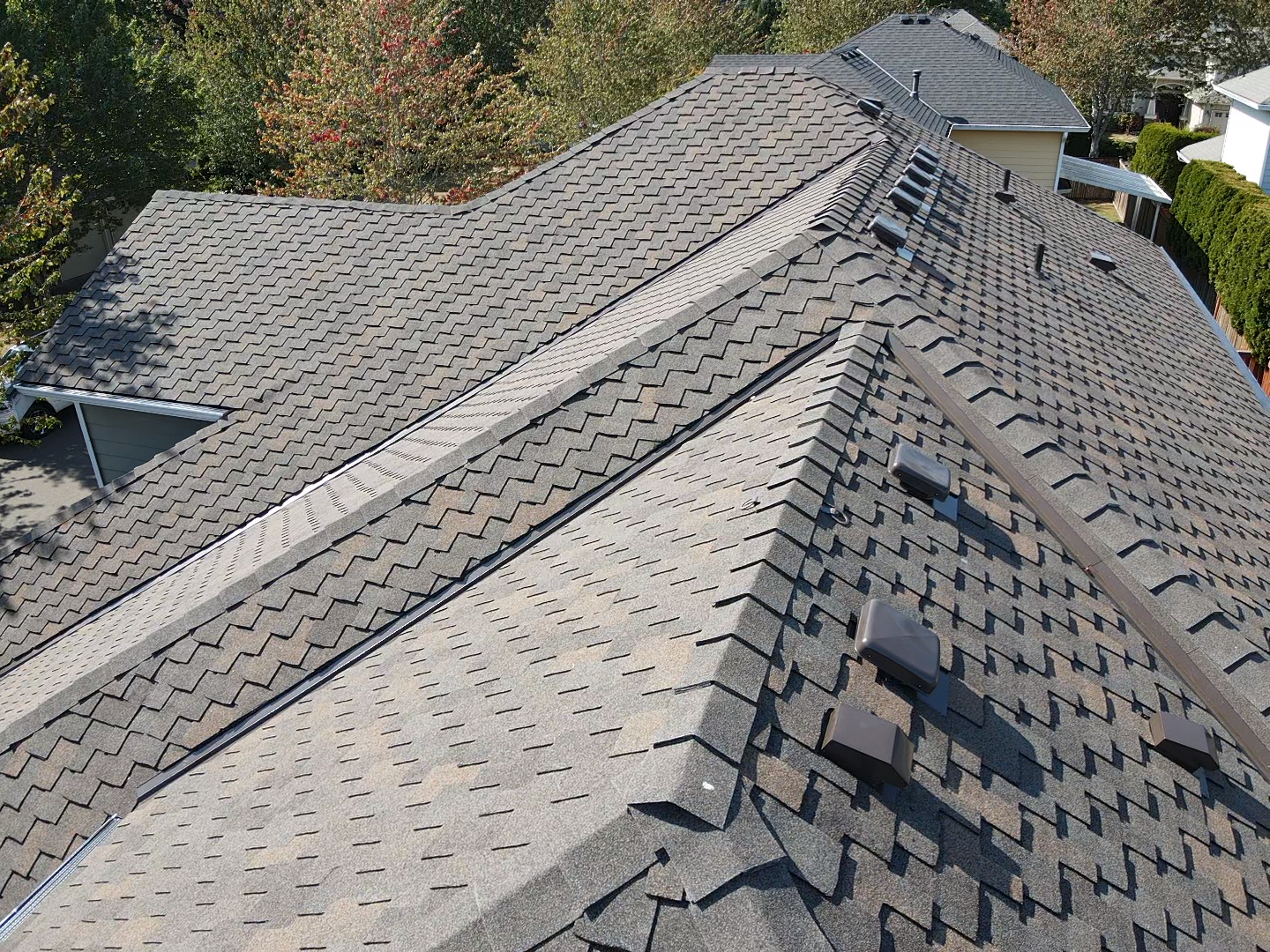 A roof with a lot of shingles on it and trees in the background.