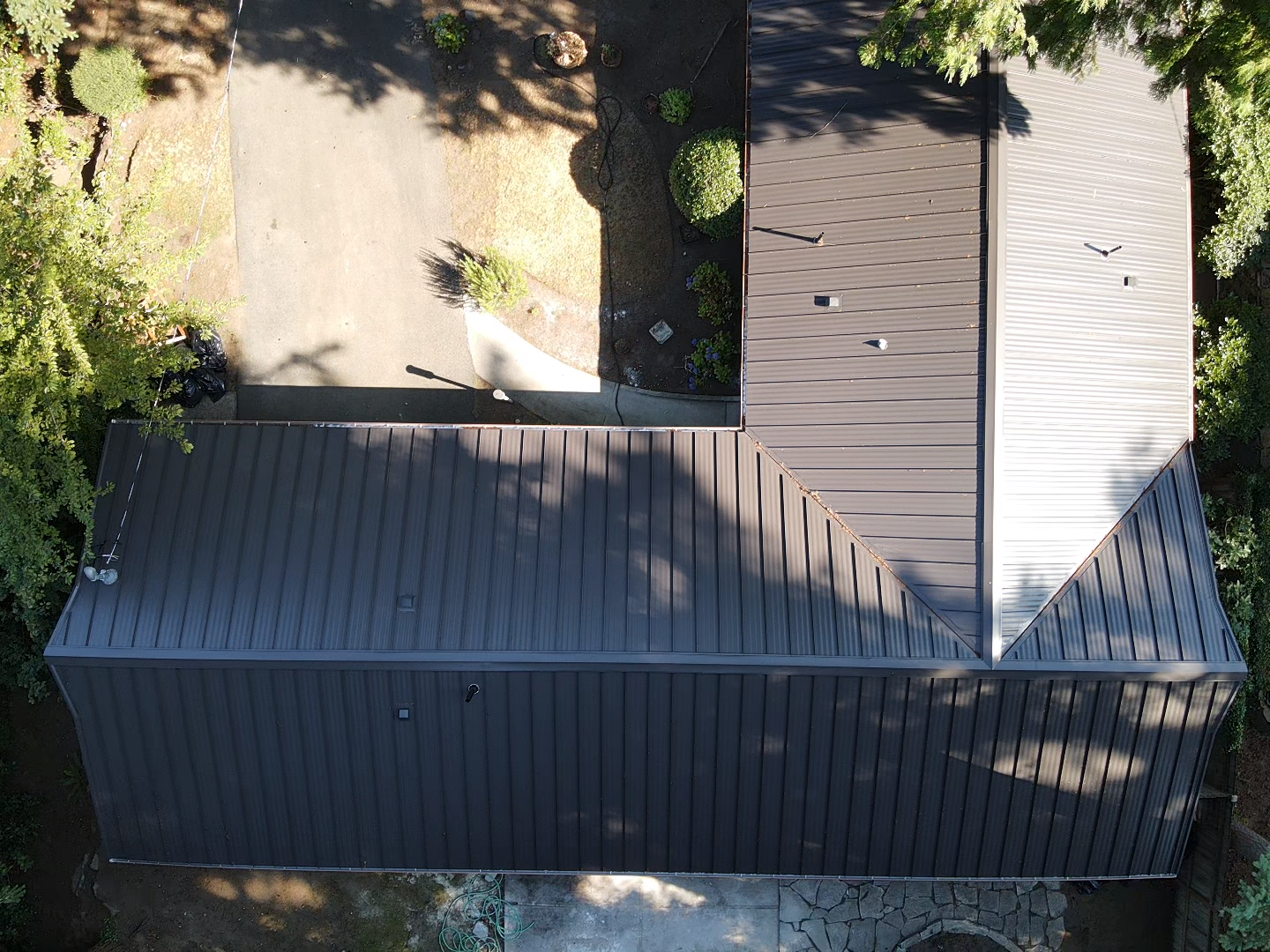 An aerial view of a house with a black roof surrounded by trees.