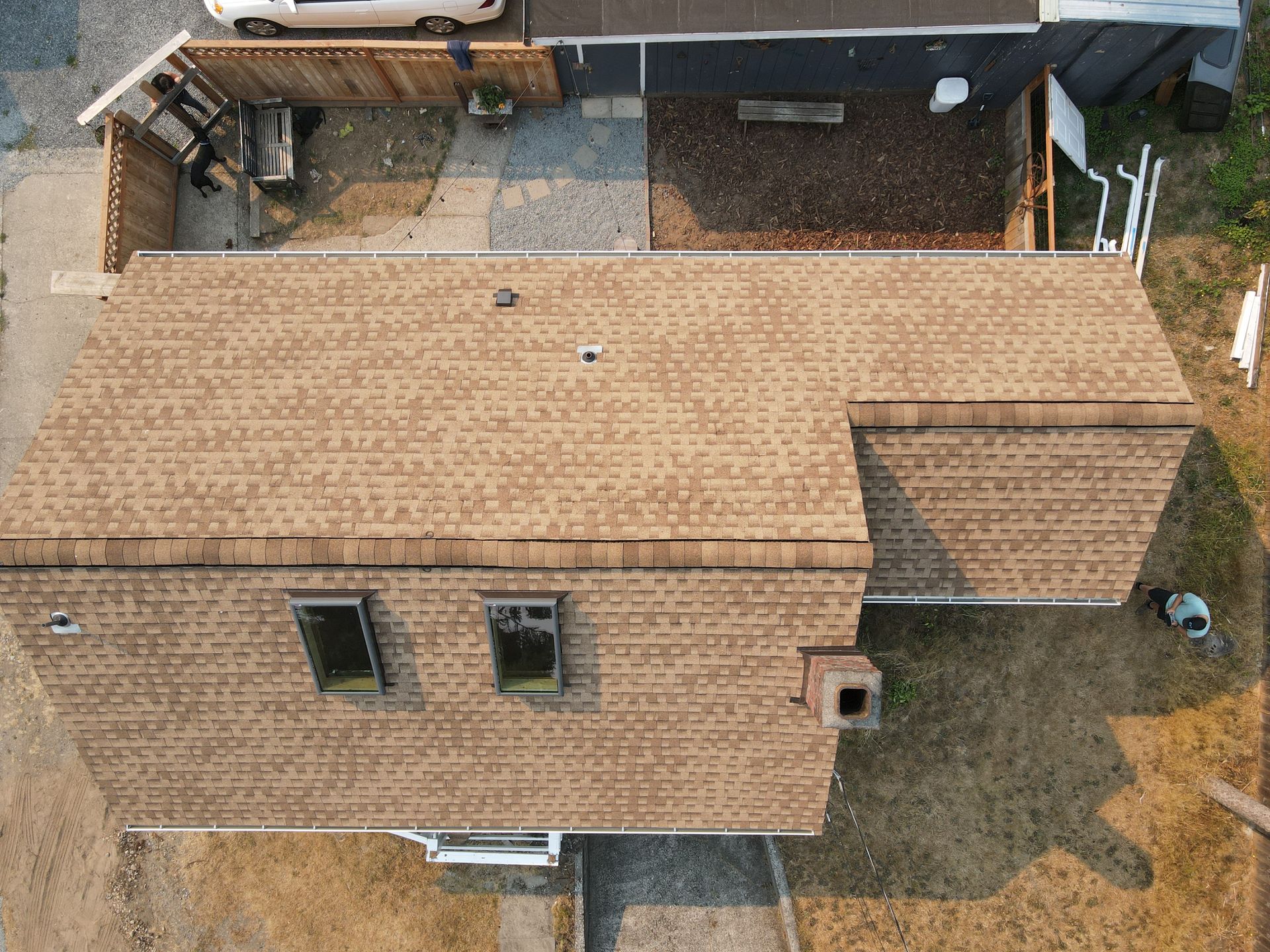An aerial view of a house with a roof and a car parked in front of it.