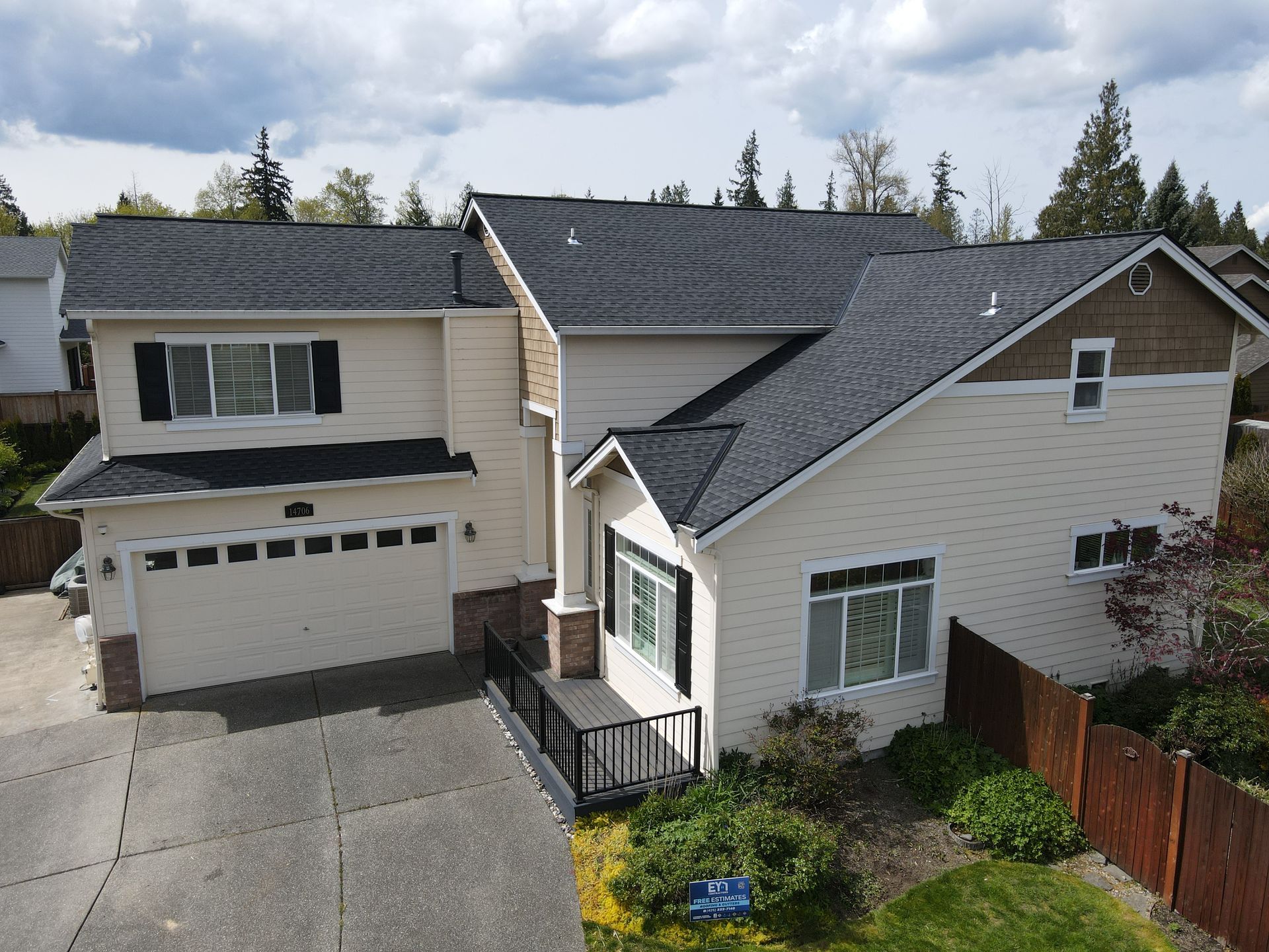 An aerial view of a large white house with a black roof.