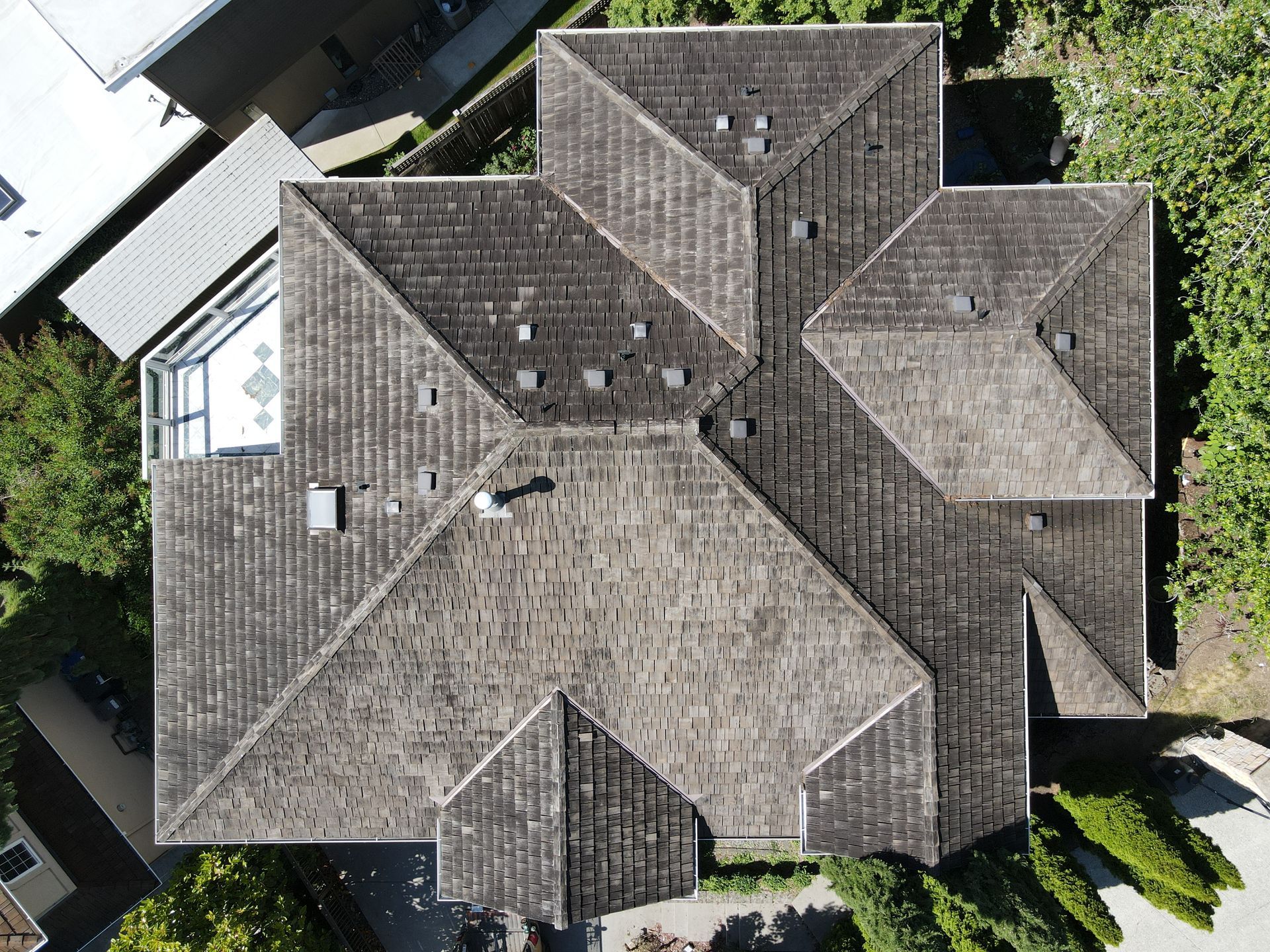 An aerial view of a large house 's roof surrounded by trees.