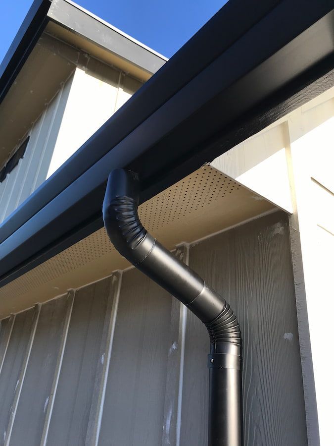 A black gutter is on the side of a house.