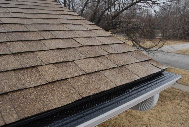 A close up of a roof with shingles and a gutter.