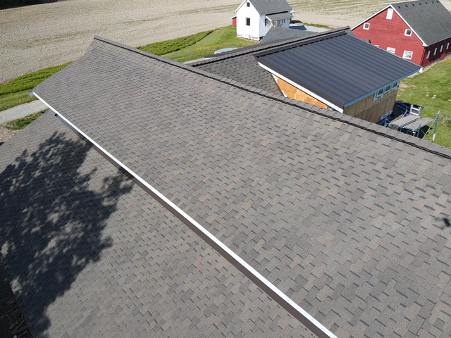 An aerial view of a roof of a house with a barn in the background