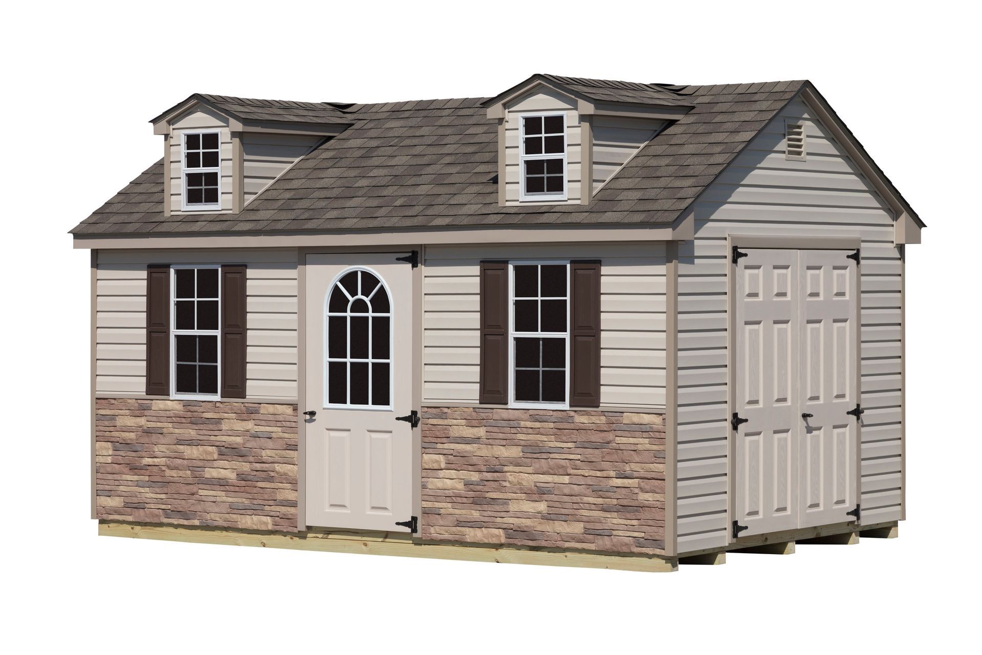 Tan and brown shed with stone base, door, windows, and dormers on a wooden base.