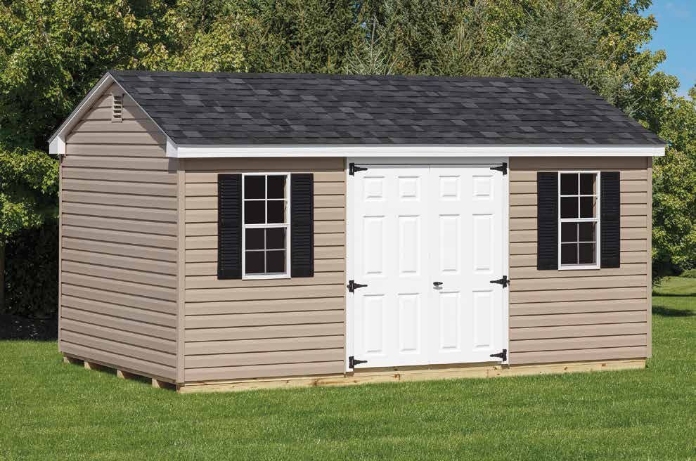 Tan storage shed with white double doors, two windows with black shutters, and black shingled roof.