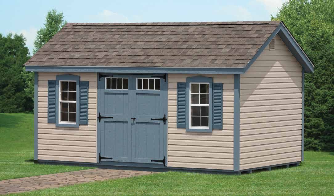 Tan shed with blue trim, door, and shutters; brown roof, on a grassy lawn.