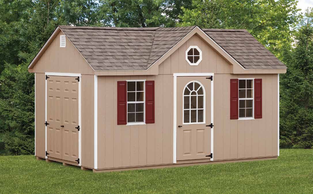 Tan shed with a gable roof, brown shingles, red shutters, and white trim, on green grass.