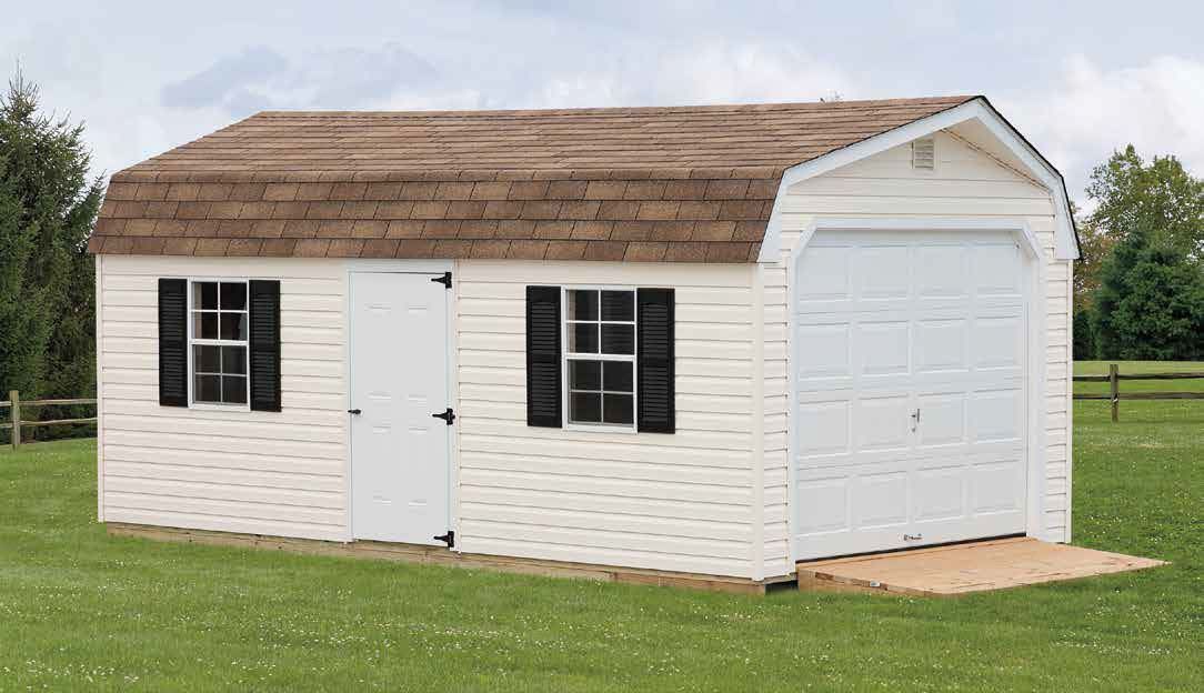 White shed with a brown roof and a garage door, set on green grass.