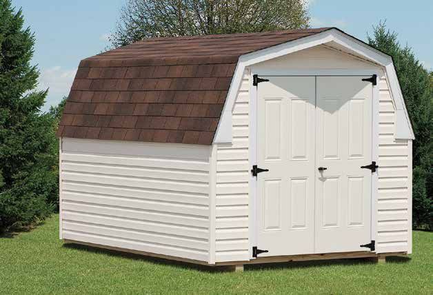White shed with brown shingle roof and double doors, on a grassy lawn with trees.