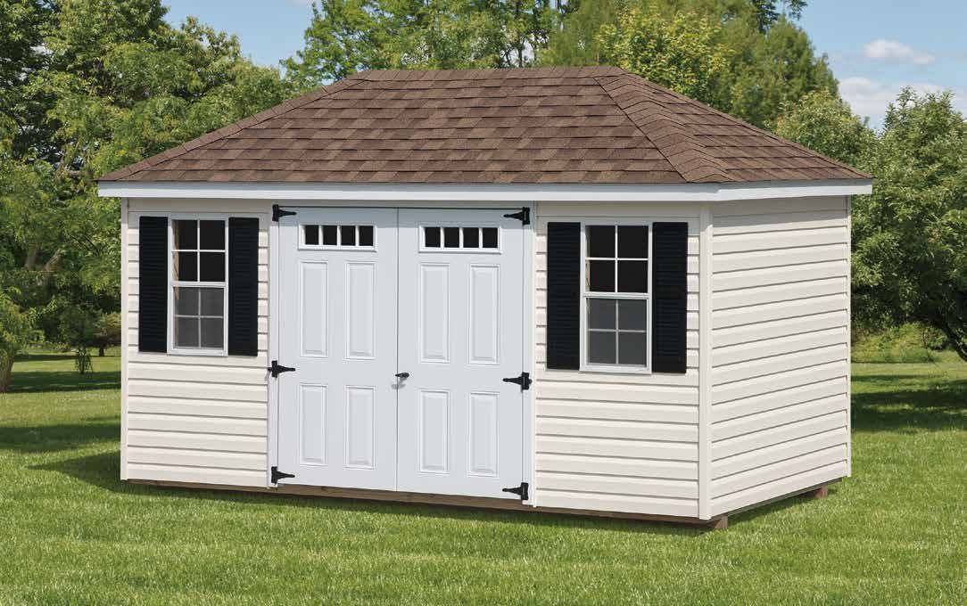 White shed with brown roof, two doors, two windows with black shutters, on a grassy lawn.