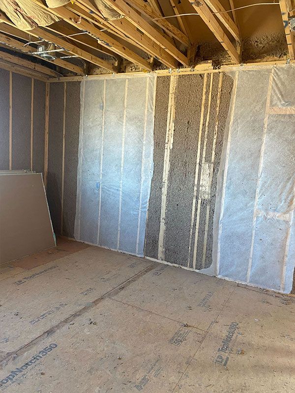 Unfinished room with exposed ceiling beams, insulation-covered walls, and bare subflooring.