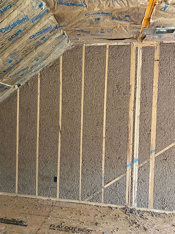 Framed wall insulation under construction with exposed studs and attic-style sloped ceiling above