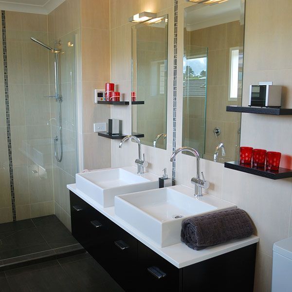 Modern bathroom with double sinks, large mirror, glass shower, and black-and-white decor