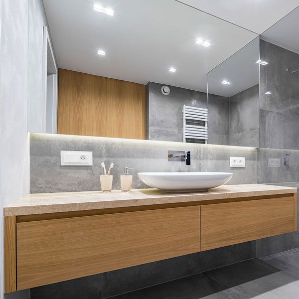 Modern bathroom with floating wood vanity, vessel sink, large mirror, and gray tile walls