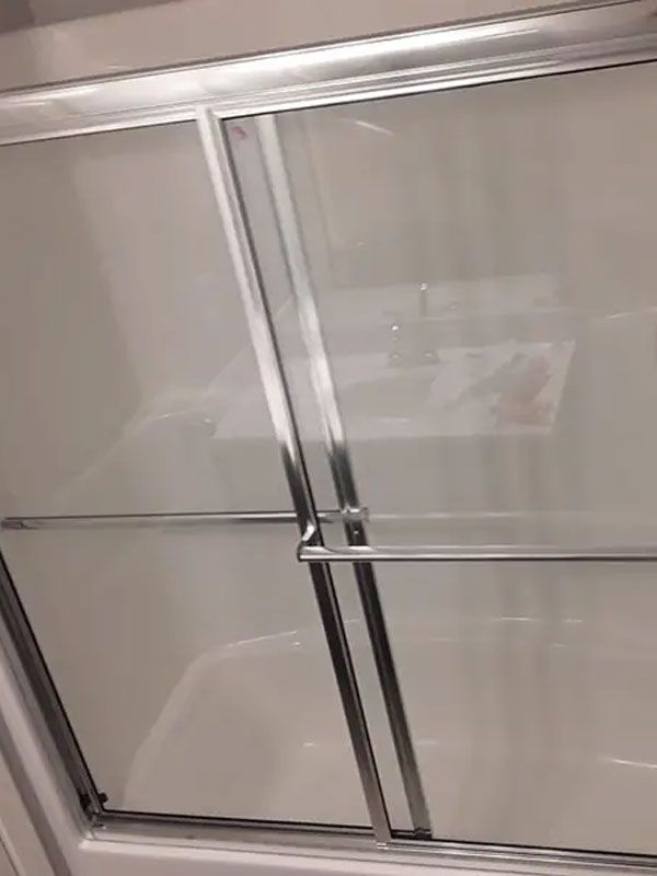 Sliding glass shower door with chrome frame and handles