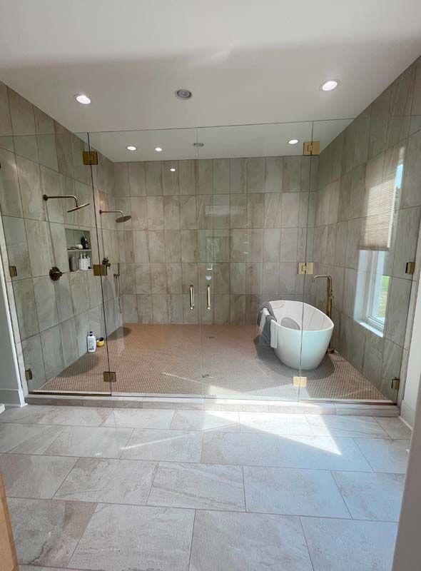 Modern tiled bathroom with glass shower, freestanding tub, and recessed ceiling lights