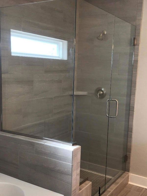Modern tiled walk-in shower with glass enclosure and small frosted window