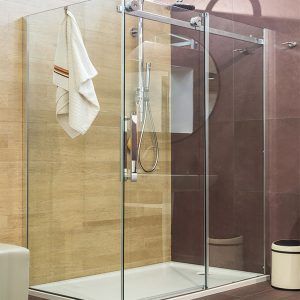 Modern bathroom shower with glass doors, beige tile, towel, and wall-mounted shower fixtures