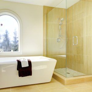 Modern bathroom with a freestanding tub, glass shower, and large arched window