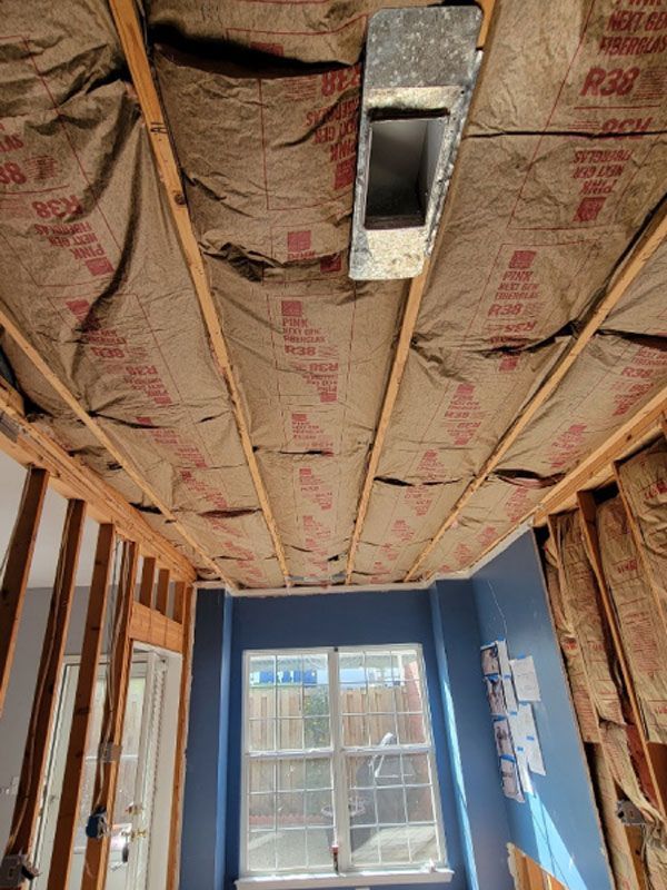 Unfinished room with exposed insulation ceiling, blue walls, a window, and a door on the left.