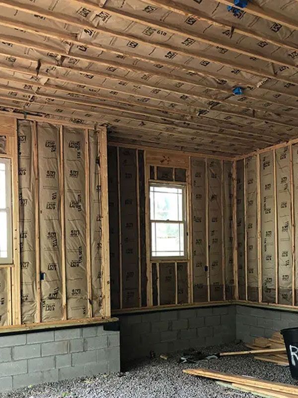 Unfinished room with exposed insulation, studs, window, and cinder block foundation wall