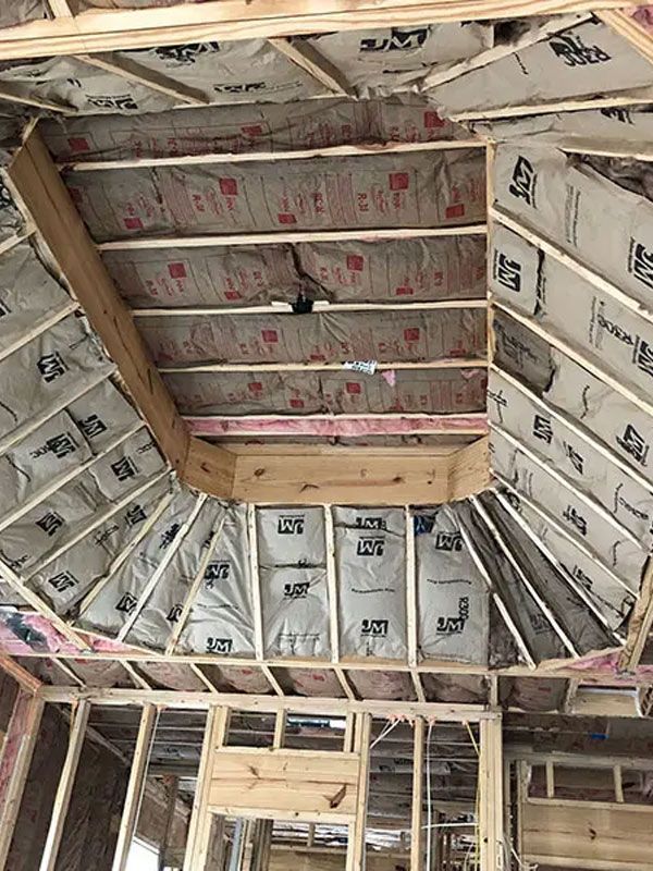 Insulated attic with exposed wooden rafters and partially framed ceiling joists