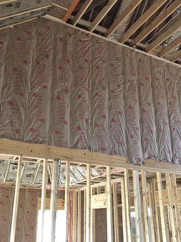 Insulated interior wall framing in a house under construction with exposed wooden rafters