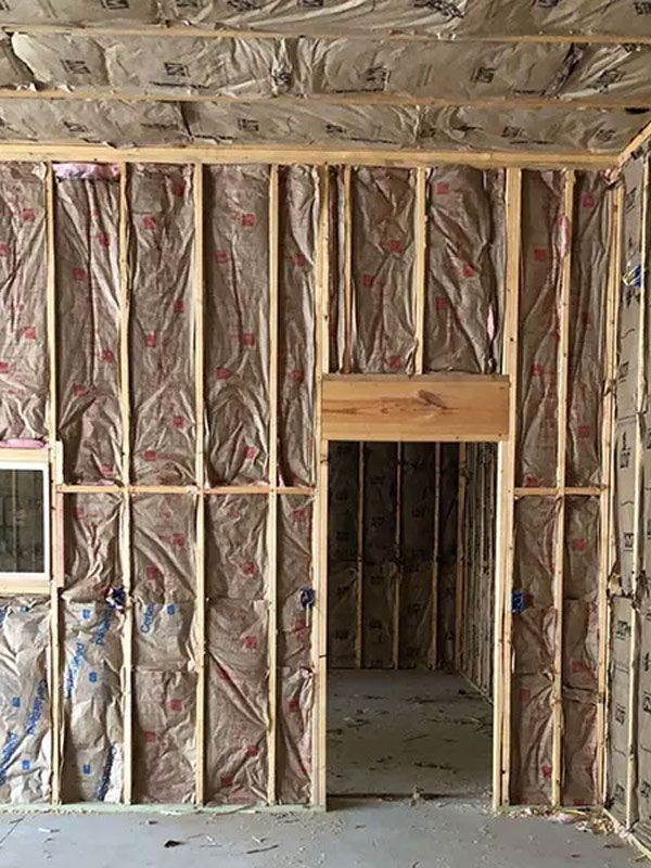 Unfinished wall framing with pink insulation and a doorway opening in a construction site