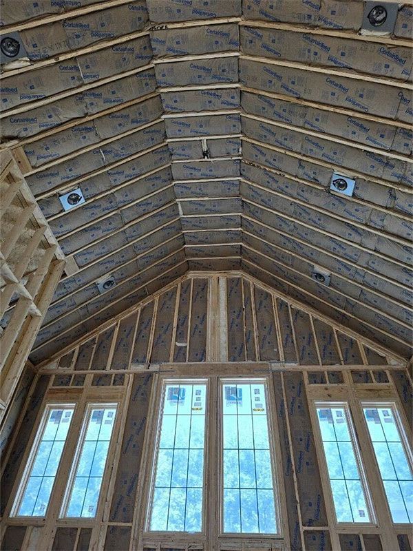 Interior view of a vaulted wooden ceiling with exposed beams and tall windows below