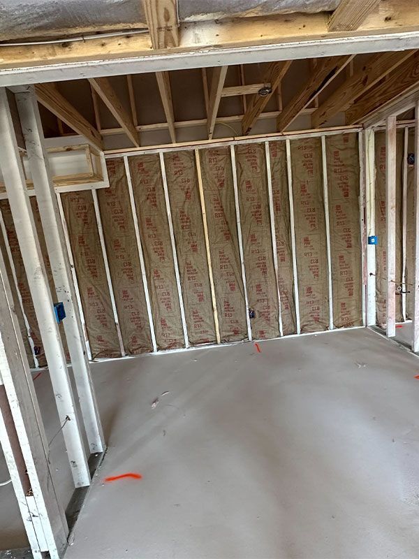 Unfinished basement room with exposed framing, insulation, and a smooth concrete floor.