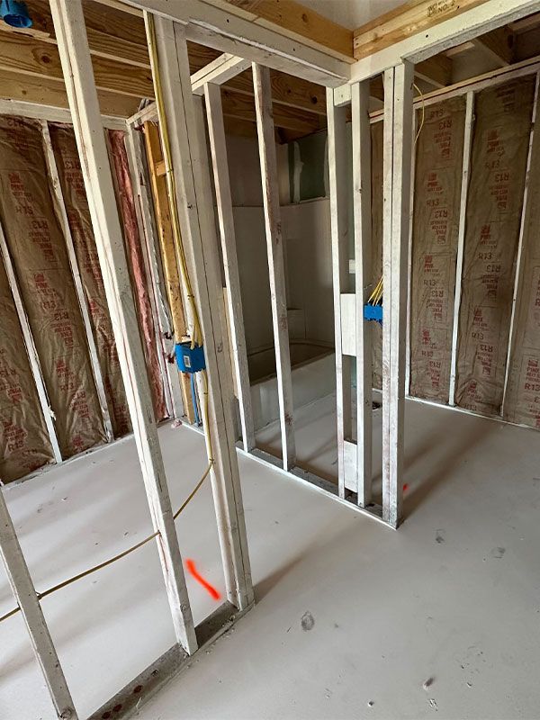 Unfinished interior framing of a house with exposed studs, insulation, and blue electrical boxes.